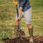 Frau arbeitet mit Fiskars Spatengabel Solid im Garten, um Erde zu lockern.