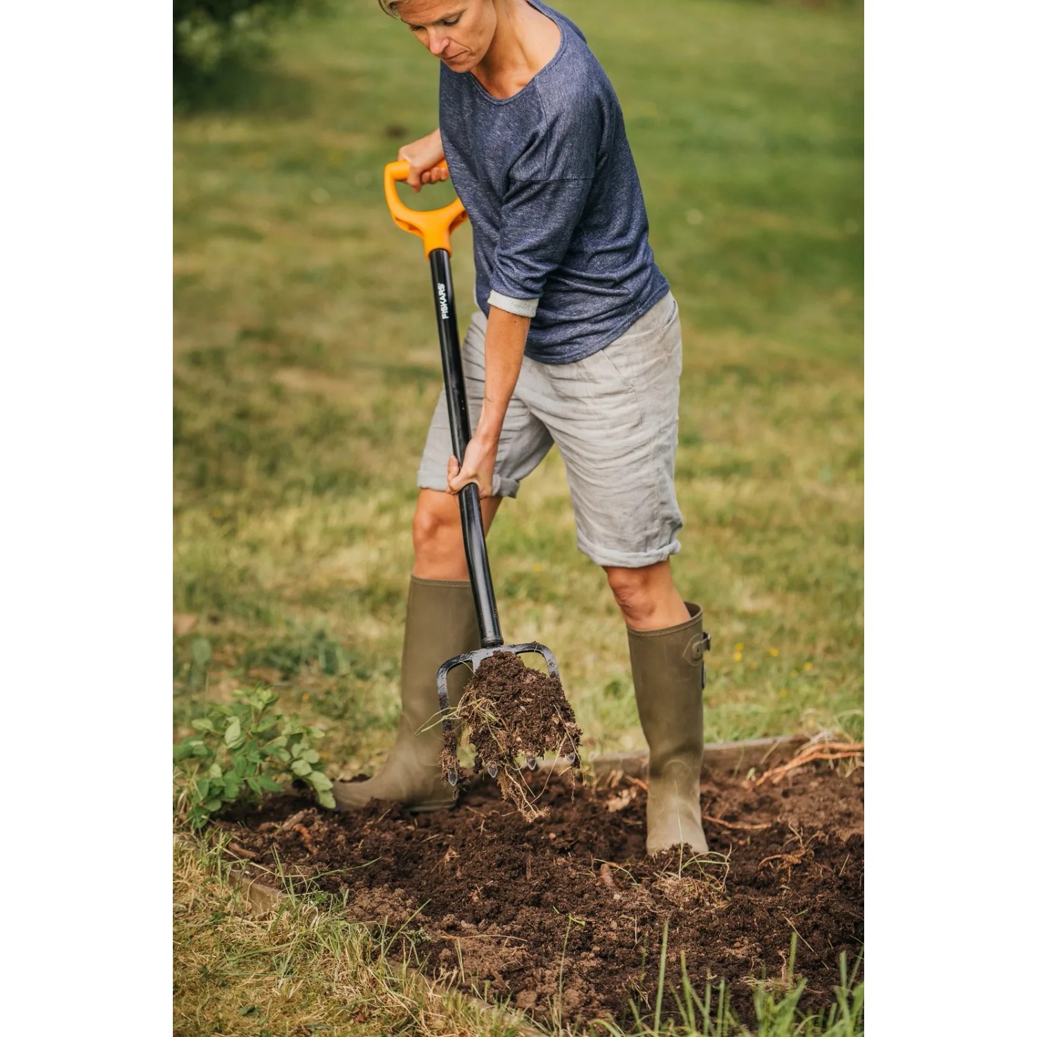 Frau arbeitet mit Fiskars Spatengabel Solid im Garten, um Erde zu lockern.