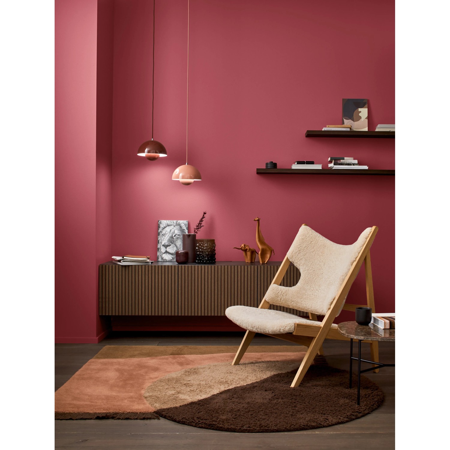 Wohnraum in Beerenrot mit Alpina Wandfarbe, Sessel und Teppich.