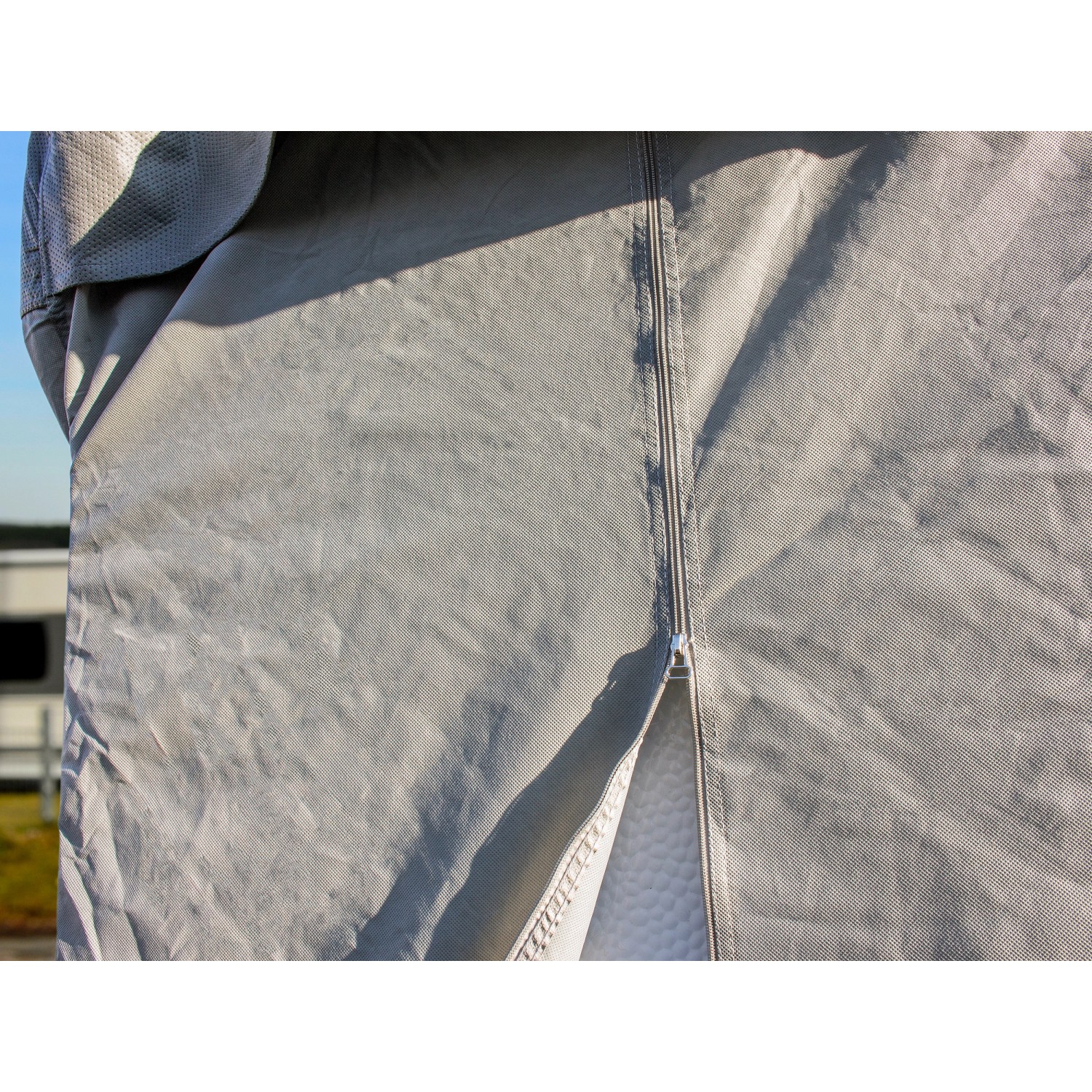 Detailaufnahme: Graue Wohnmobil Schutzhülle mit Reißverschluss und atmungsaktivem Textilgewebe.