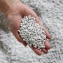 Hand hält Blähton-Granulat, geeignet für Ecopots Pflanztöpfe und Pflanzsäulen.