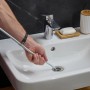 Rohrreinigungsspirale aus Stahl im Einsatz am Waschbecken, silberfarben.