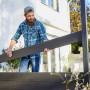 Mann montiert anthrazitfarbenen Vierkant-Pfosten (7x7x176 cm) für WPC-Zaun. Zubehör für Zaunbau.