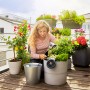 Frau installiert Gardena Solar-Bewässerung Aqua Bloom auf Balkon mit Pflanzen.