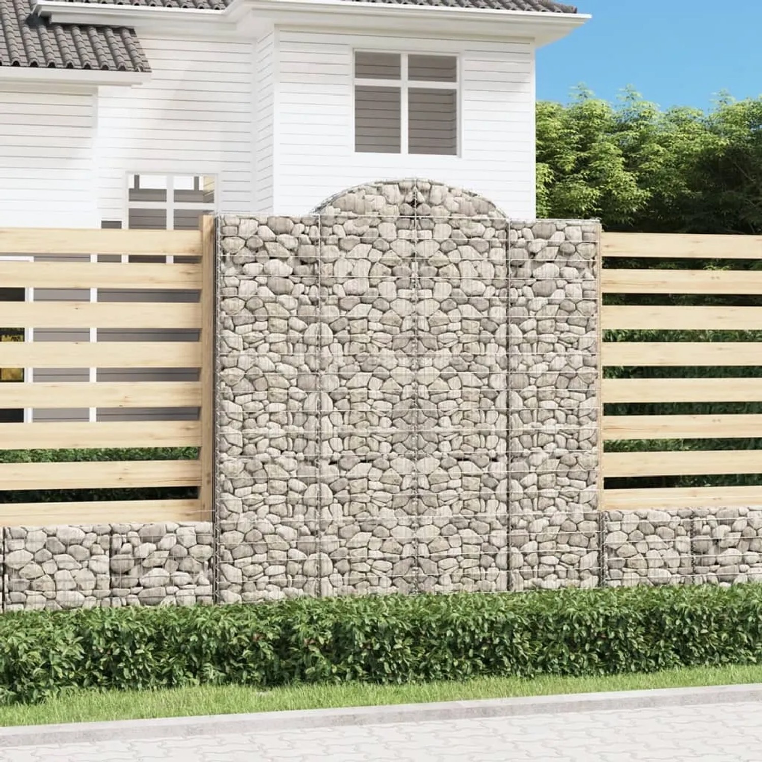 Gabione mit Hochbogen als dekorative Gartenbegrenzung, gefüllt mit Steinen.