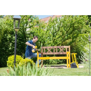 Mann lackiert Holzbank mit Wagner Farbsystem Sprühgerät W950 Flexio im Garten.