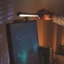 Schwarze Philips Edison Bildschirmleuchte am Monitor mit Hand zur Bedienung. LED-Tischleuchte.