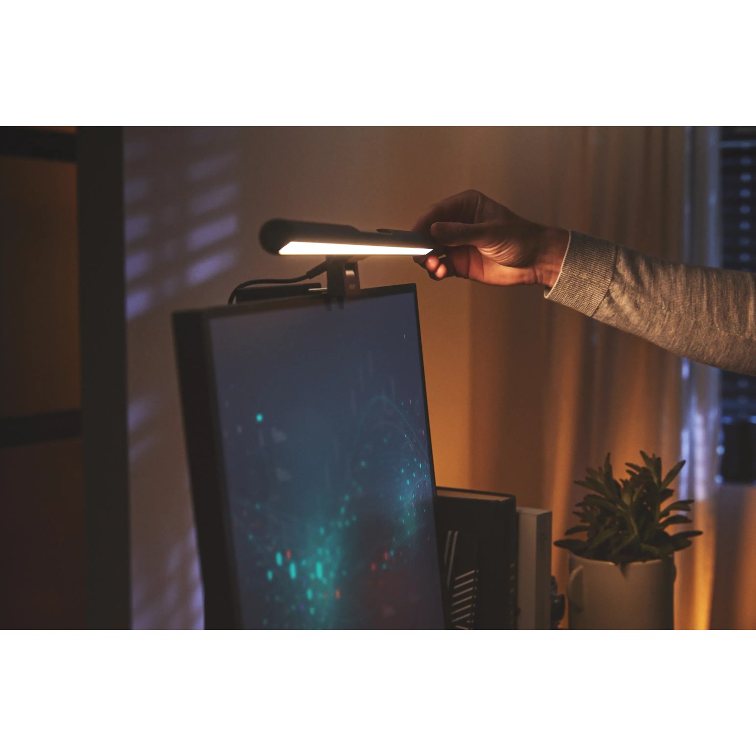 Schwarze Philips Edison Bildschirmleuchte am Monitor mit Hand zur Bedienung. LED-Tischleuchte.