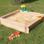 Rechteckiger Sandkasten aus Fichtenholz (120x120 cm) mit Spielzeug auf einer grünen Wiese.
