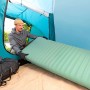 Mann legt grüne Bestway Luftmatratze ComforTrek in ein Zelt. Camping & Outdoor Zubehör.