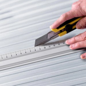 Zuschneiden einer transparenten KARAT Doppelstegplatte (6mm) mit Cutter und Lineal.