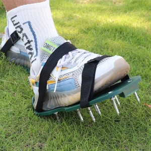 Rasenlüfterschuhe von Relaxdays in Schwarz, Grün und Silber am Fuß auf Rasen. Verstellbare Stachelschuhe zur Rasenbelüftung.