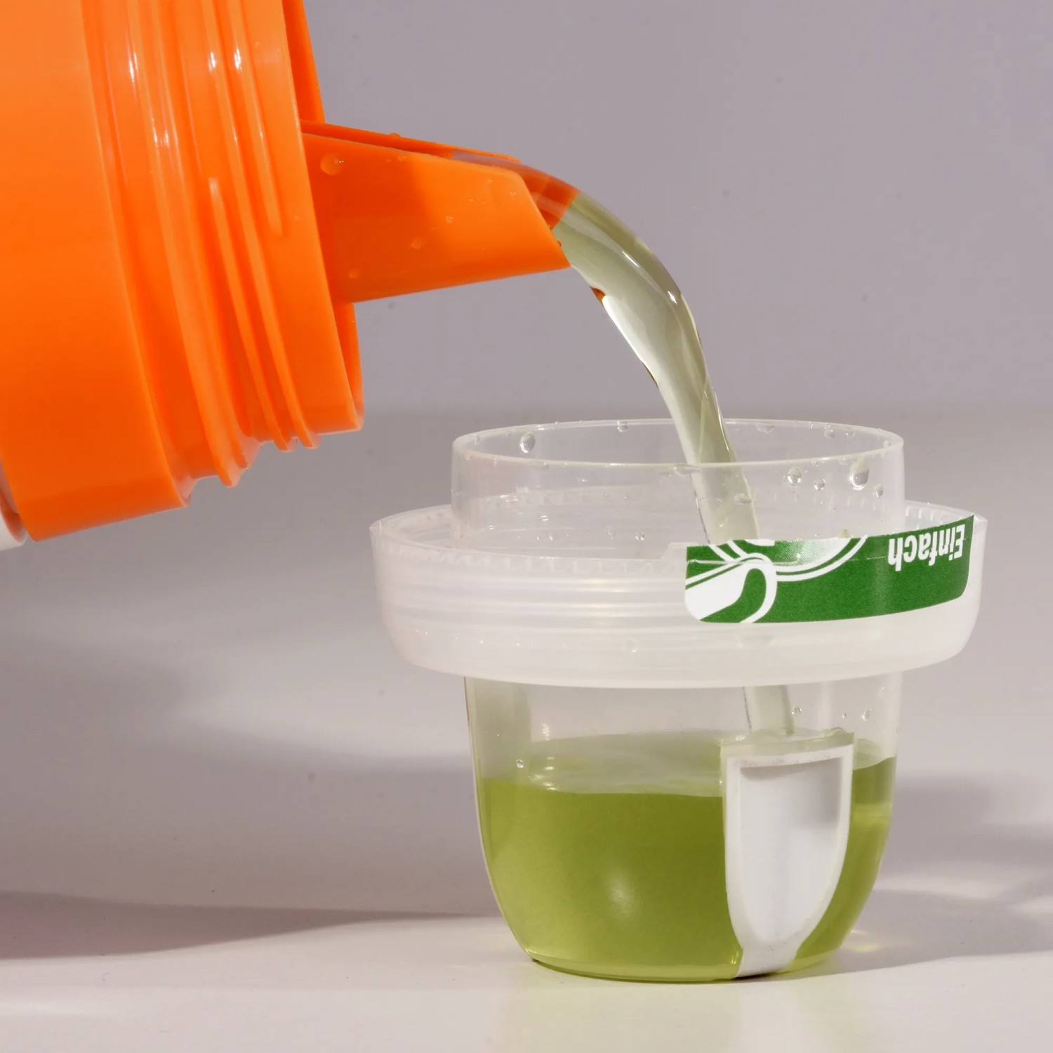 Dosierung von Compo Kakteendünger aus einer orangefarbenen Flasche in eine Messkappe.