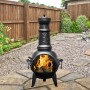 Buschbeck Mexiko-Ofen Leaf 107: Schwarze Stahl-Feuerschale mit Grillfunktion und Blattmuster im Garten.