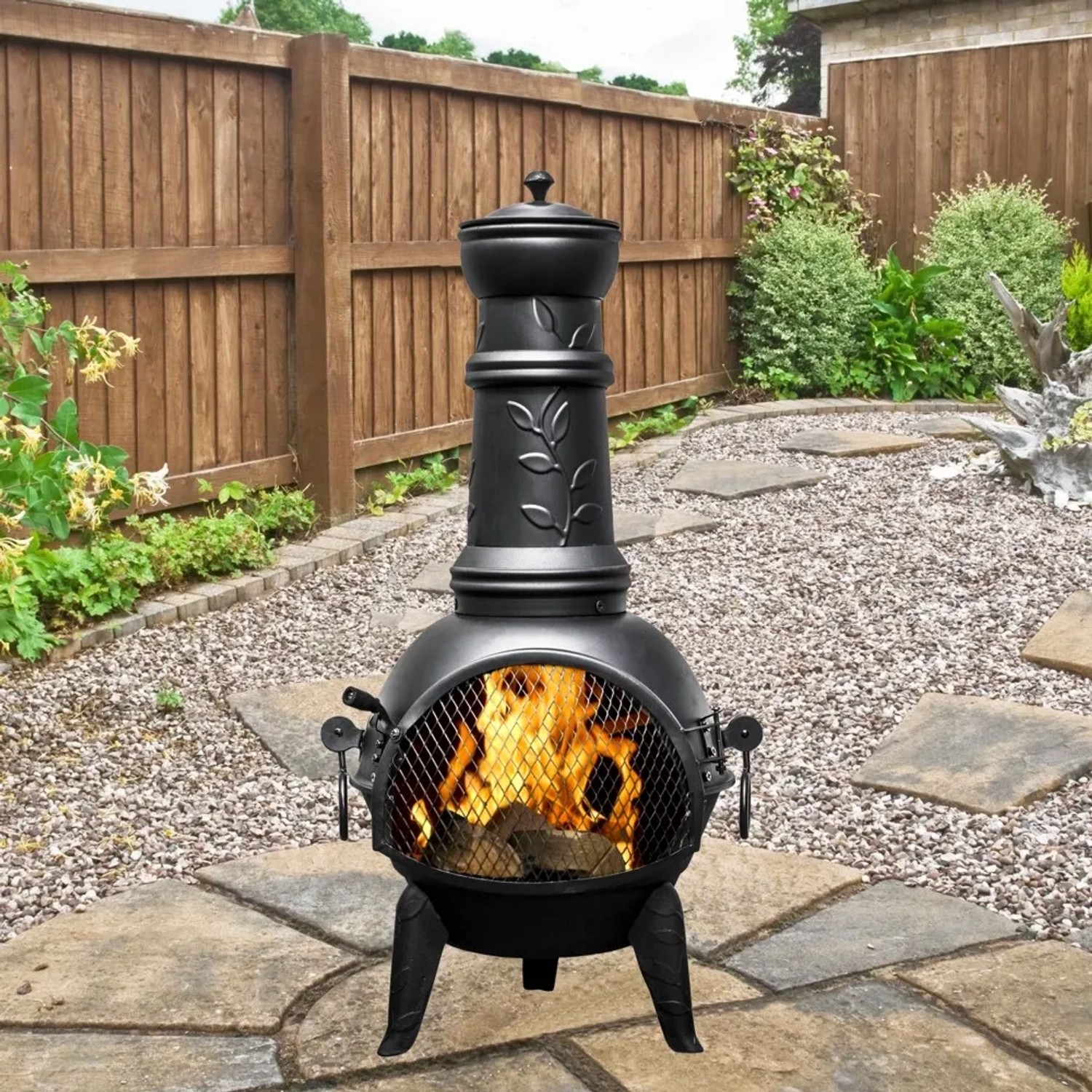 Buschbeck Mexiko-Ofen Leaf 107: Schwarze Stahl-Feuerschale mit Grillfunktion und Blattmuster im Garten.