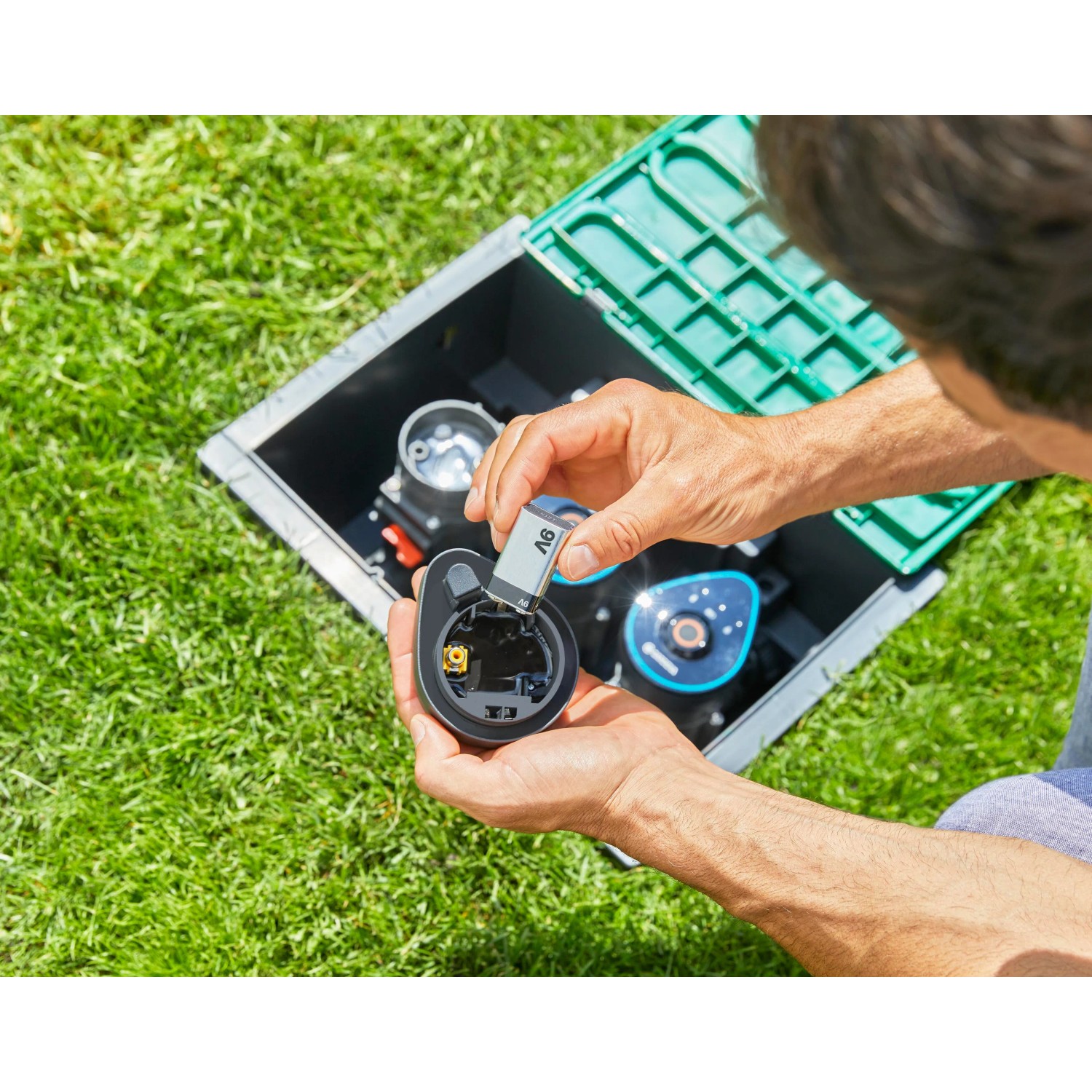 Mann setzt 9V Batterie in Gardena Bewässerungsventil 9 V Bluetooth im Garten ein.