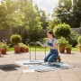 Frau baut grünes Balkongewächshaus aus Stahl und PVC im Garten zusammen. Einfacher Aufbau für Pflanzenanzucht.
