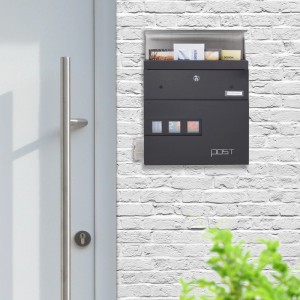 Schwarzer Relaxdays Wandbriefkasten aus Stahl mit Zeitungsfach an einer weißen Backsteinwand.