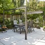 Siena Garden Pergola Schattenmanufaktur 315x315x218cm mit Esstisch und Stühlen im Garten.