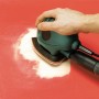 Black+Decker Schleifmaus mit LUX Schleifauflagen-Set im Einsatz auf roter Oberfläche.