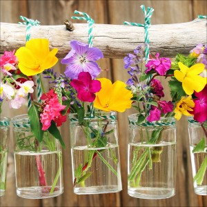 Leinwandbild mit bunten Blumen in Gläsern, aufgehängt an einem Ast. Dekorative Wanddeko.