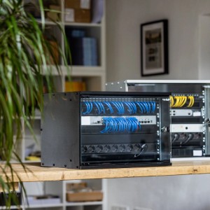 HMF 7HE Netzwerkschrank, unmontiert, mit Glasfront und blauen Netzwerkkabeln.