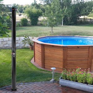 Schwarze Planet Pool Solardusche (20 l) neben Pool im Garten.