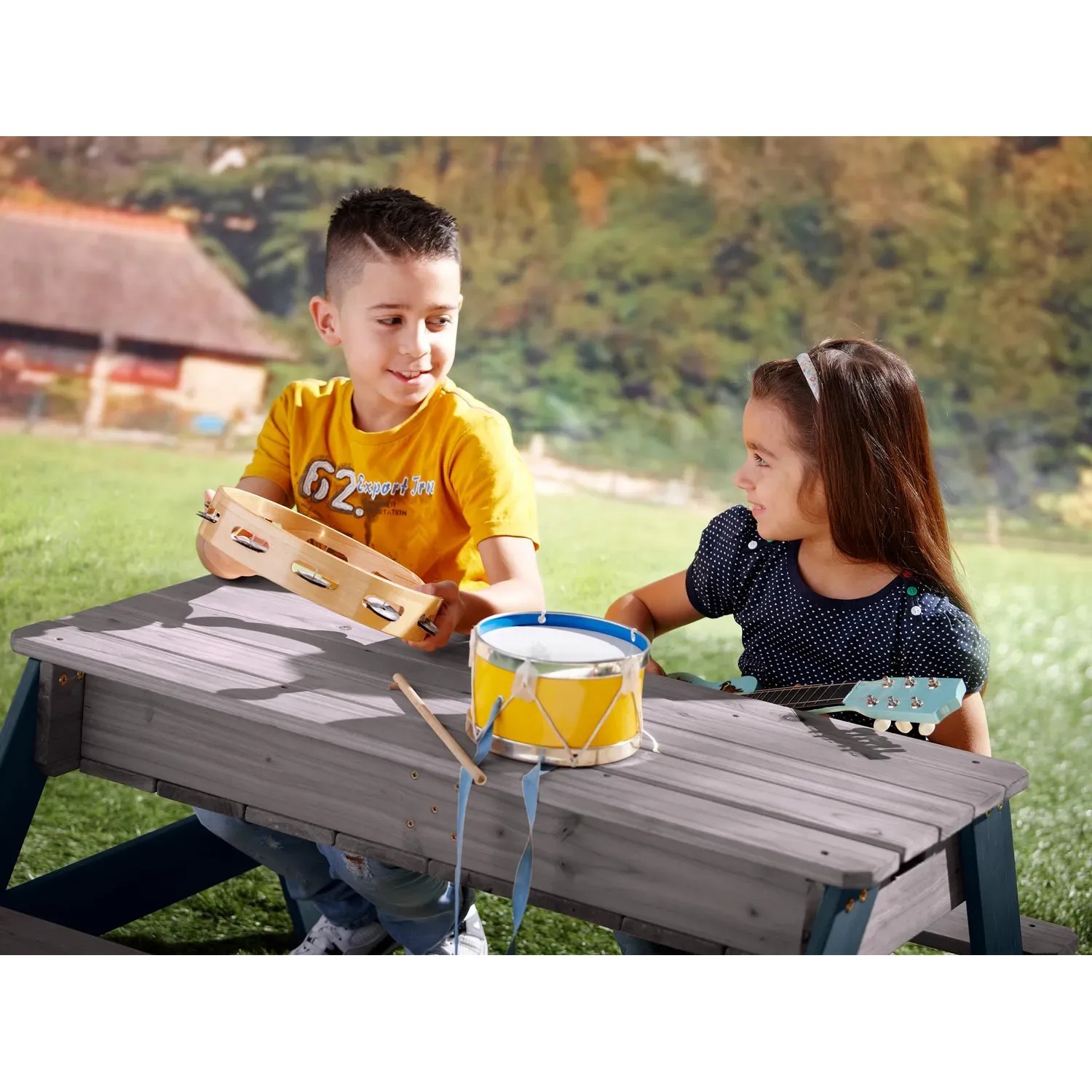 Axi Sand- und Wasser-Picknicktisch Nick grau mit Sonnenschirm, spielende Kinder mit Musikinstrumenten.