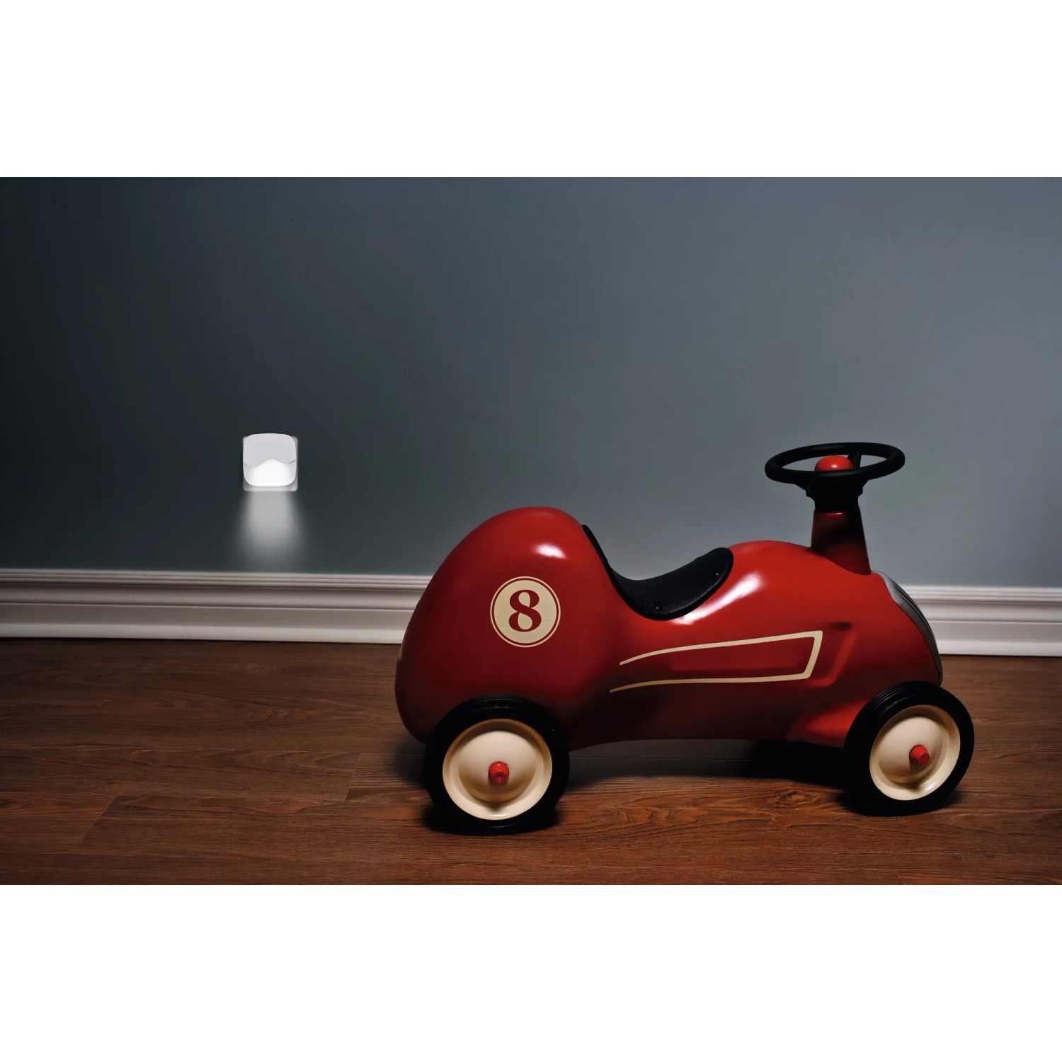 Osram LED-Nachtlicht Lunetta Wave an Wand, daneben rotes Kinderrutscherauto.
