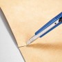 LUX Cuttermesser (9 mm) mit blauem Kunststoffgehäuse schneidet beiges Material.