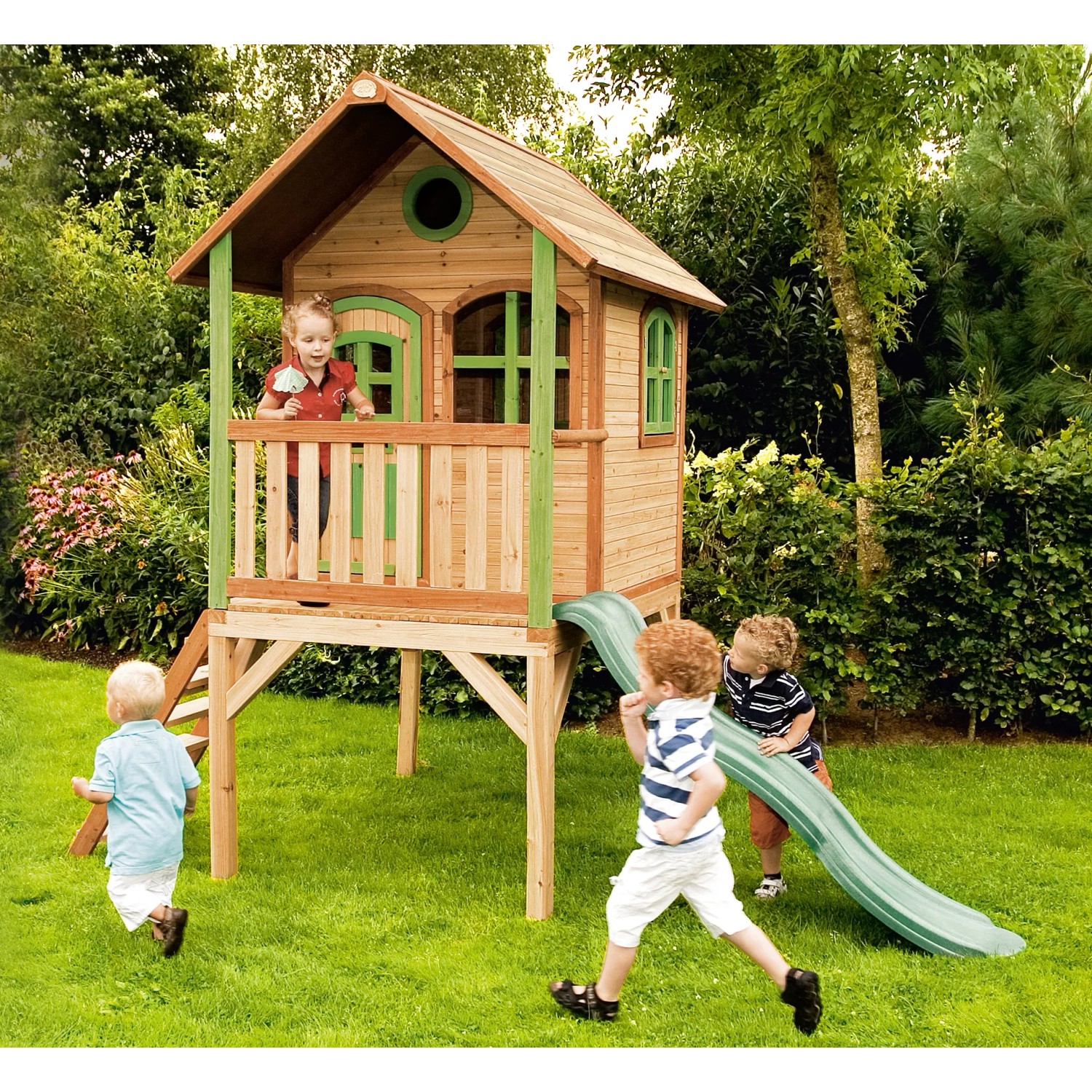 Spielhaus Laura mit Leiter und Rutsche im Garten mit spielenden Kindern.
