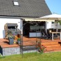 Schwarzer Eisen-Rosenbogen mit Sitzbank für 2 Personen, verziert, als Rankhilfe für Kletterrosen im Garten auf Rasen.