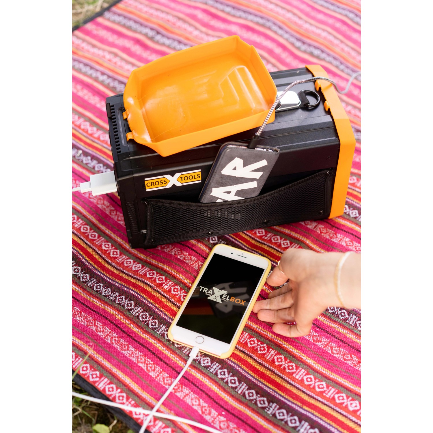 Cross Tools Travelbox 500 Power Station lädt Handy auf Picknickdecke.