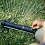 Fiskars Comfort S-M oszillierender Regner in Schwarz-Orange im Einsatz auf Rasen.