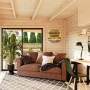 Innenansicht: Palmako Holz-Gartenhaus mit Pultdach als Wohnraum mit Sofa und Schreibtisch.