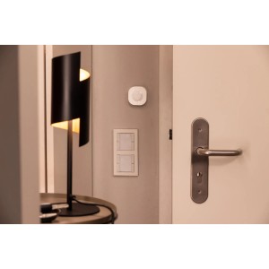 Osram Smart+ Bewegungssensor WiFi an Wand montiert, neben Lampe und Türgriff.