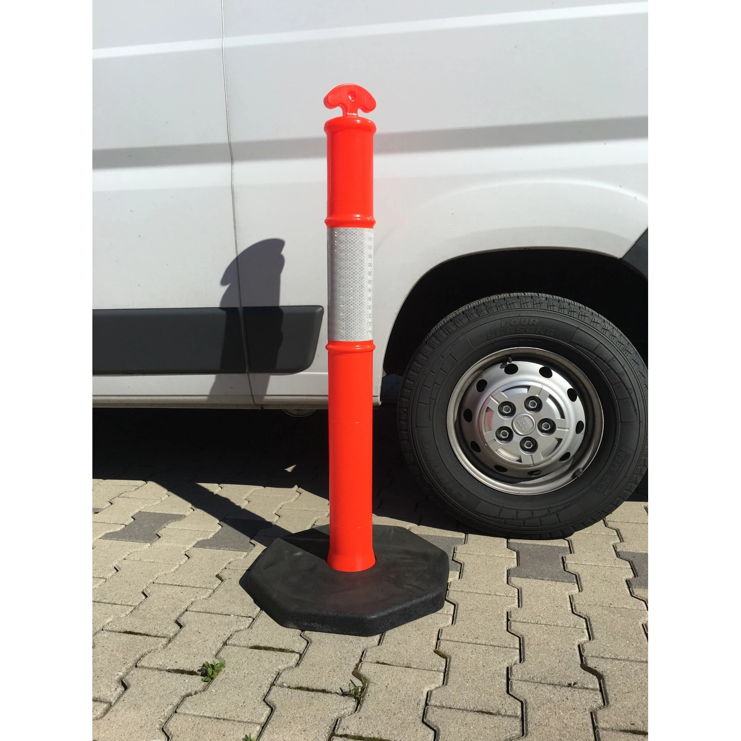 Oranger UvV FLEX Absperrpfosten mit Reflexstreifen und schwarzer Fußplatte.