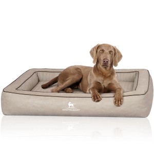 Hund liegt entspannt im grauen Knuffelwuff Hundebett Montego aus Kunstleder, orthopädisch.