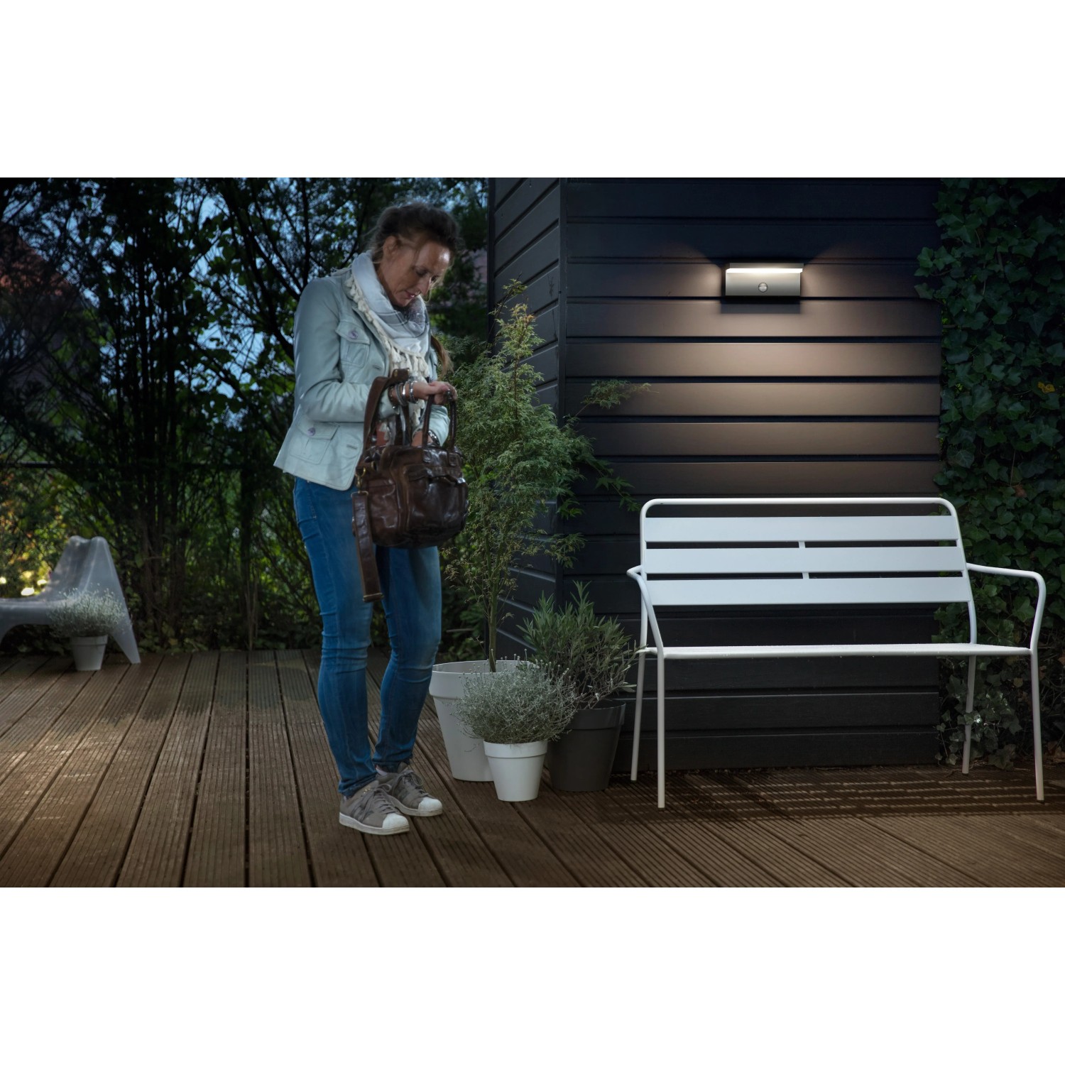 Philips myGarden Bustan LED-Außenwandleuchte mit Bewegungsmelder an dunkler Hauswand.