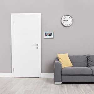 Byron Video-Türsprechanlage mit 7-Zoll-Display, kabelgebunden, an grauer Wand im Wohnzimmer.