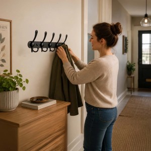 Schwarze Edelstahl Wandgarderobe mit 5 Dreifachhaken im Flur. Frau hängt Jacke auf. 2er Set für Ordnung.