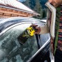 Mann benutzt Kärcher EDI 4 elektrischen Eiskratzer an einer vereisten Autoscheibe.