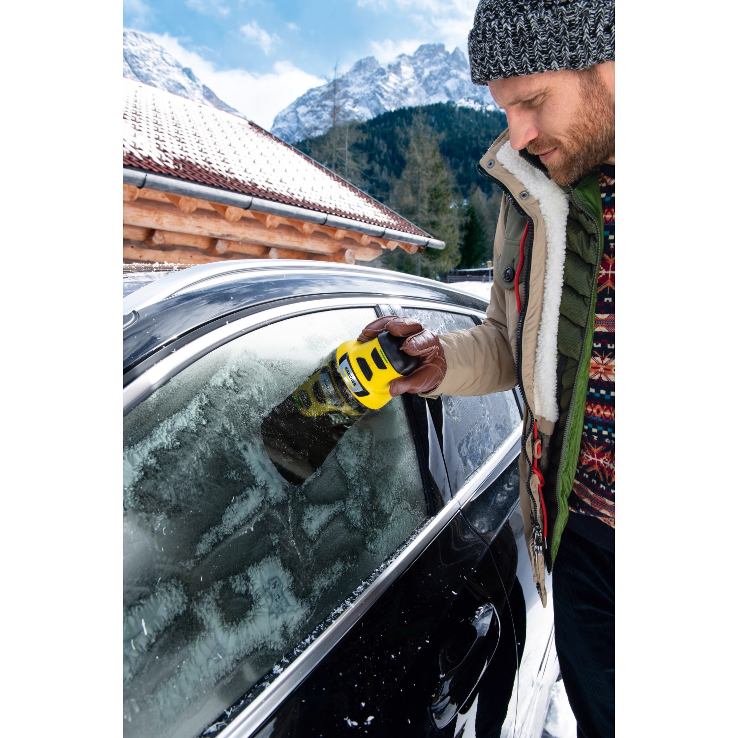 Mann benutzt Kärcher EDI 4 elektrischen Eiskratzer an einer vereisten Autoscheibe.