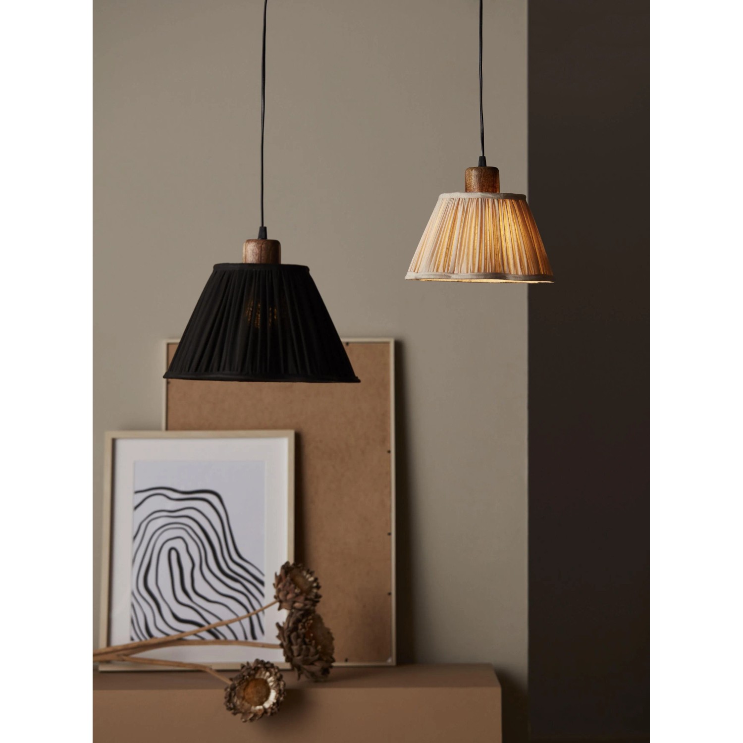 Zwei PR Home Siv Pendelleuchten: eine schwarze und eine helle, mit plissiertem Schirm und Holzdetails.