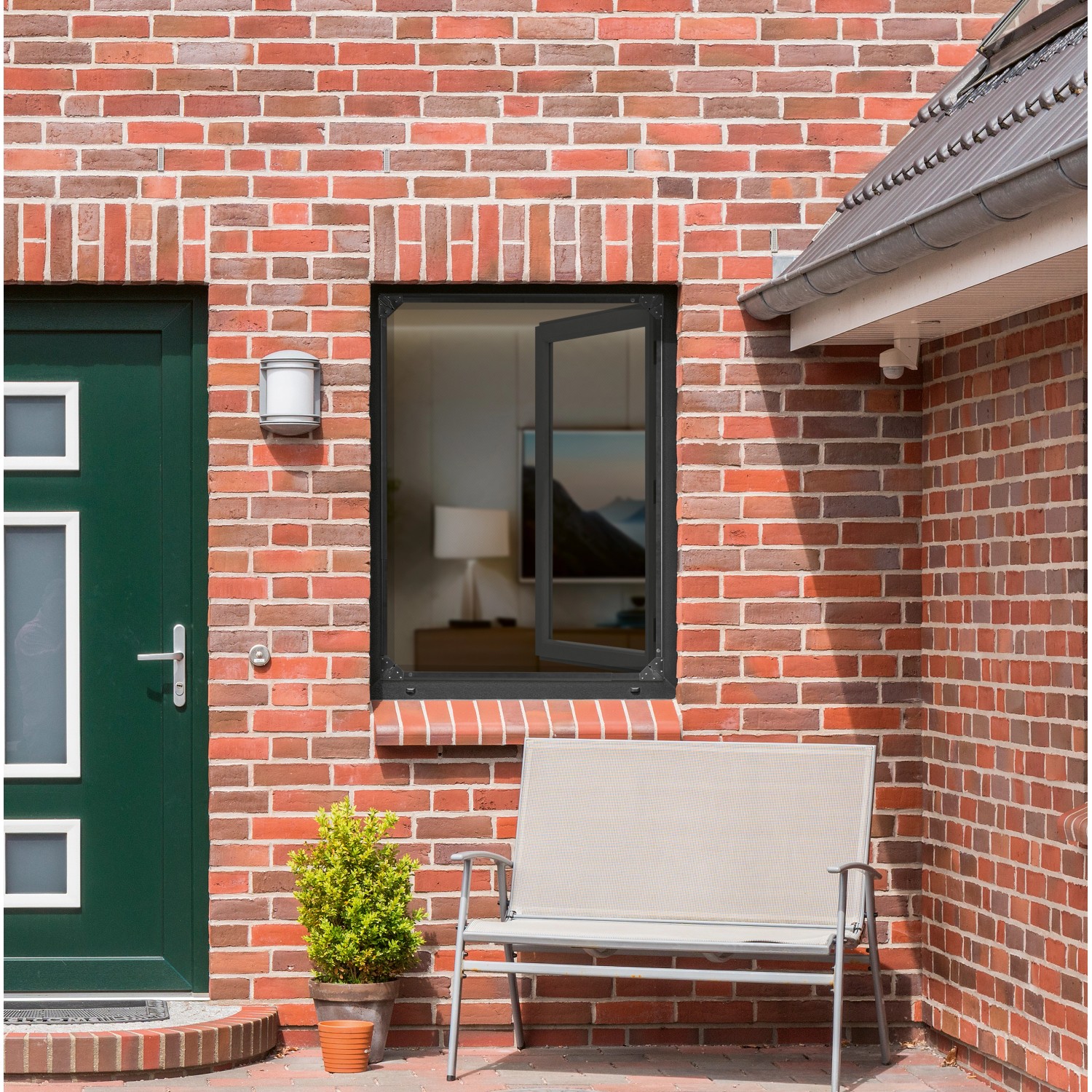 Anthrazitfarbenes Easymaxx Moskitonetz Magic Fit am Fenster eines Backsteinhauses.