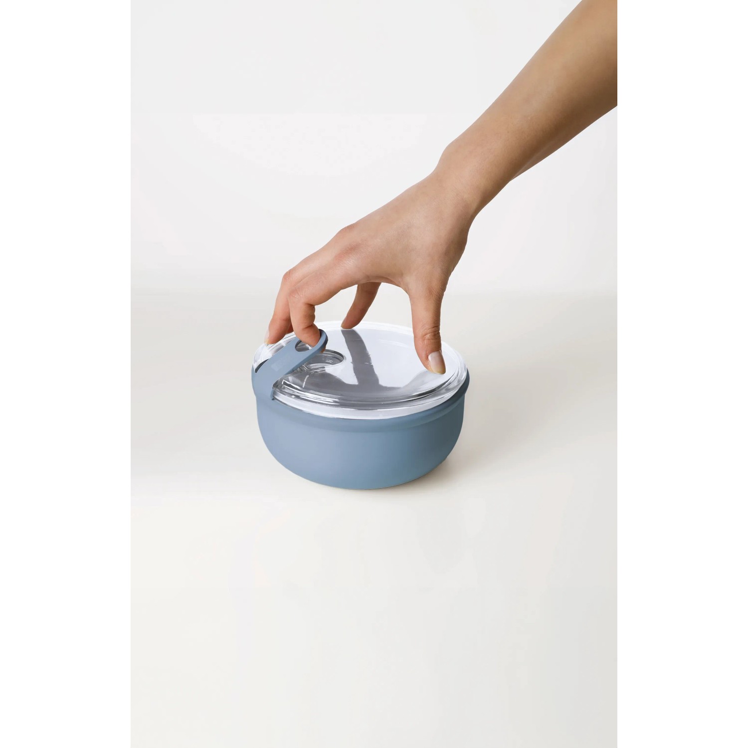 Runde, blaue Rotho Frischhaltedose Ela (0,75 l) mit transparentem Deckel wird von Hand verschlossen.