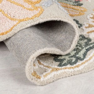 Nahaufnahme des Flair Rugs Wollteppichs Daphne Floral, gerollt, zeigt mehrfarbiges Blumenmuster, geformte Kanten und Wollstruktur.