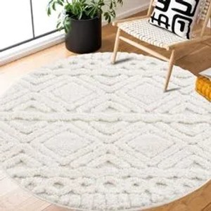 Runder, pastellcremefarbener Hochflorteppich mit Boho-Rautenmuster (120x120 cm).