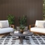Terrasse mit WPC Wandpaneel in Eiche Walnuss, Sesseln und Tisch. Outdoor-Design mit Dekor-Paneelen.