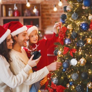 Familie dekoriert Weihnachtsbaum mit bruchsicheren Kunststoff-Weihnachtskugeln in Schwarz-Weiß für festliche Freude.
